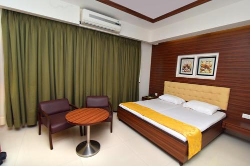 a bedroom with a bed and a table and a chair at Hotel Udupi Residency near Shri Krishna Mata, Udupi in Udupi