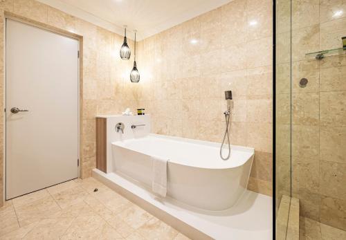 a white bath tub in a bathroom with a shower at Duxton Hotel Perth in Perth