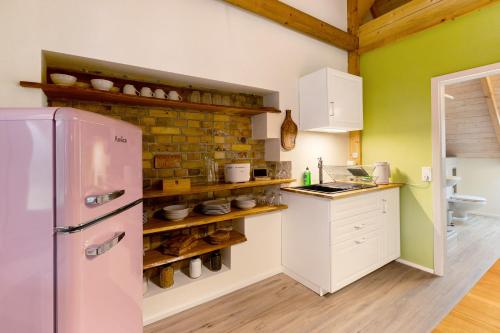 a kitchen with a pink refrigerator and a brick wall at Fewo am Flämingrand in Zahna-Elster