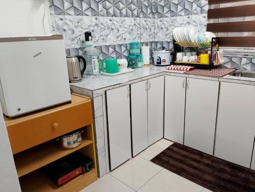a kitchen with white cabinets and a refrigerator at D'Maryam Homestay in Muar
