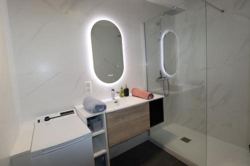 une salle de bain blanche avec un lavabo et une douche dans l'établissement Le Raspail By Tranquil at Home, Parking - Plage, à La Baule
