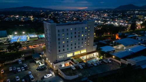 a large white building with a parking lot at night at Holiday Inn Uruapan by IHG in Uruapan del Progreso