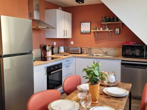 une cuisine avec une table avec des chaises et un réfrigérateur dans l'établissement Les clés de la boulangerie, à Boulogne-sur-Mer