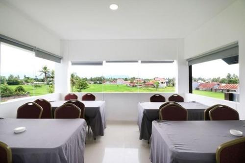 a dining room with tables and chairs and large windows at RedDoorz Plus Syariah at Polamas Andalas in Padang