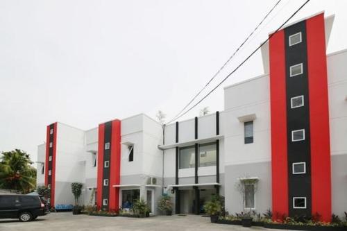 a white and red building with a car parked in front at RedDoorz Plus Syariah at Polamas Andalas in Padang