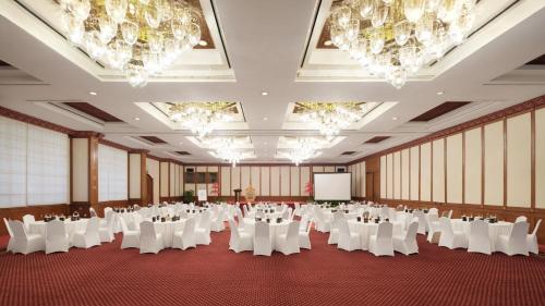 a conference room with white tables and chairs and a screen at Ayodya Resort Bali in Nusa Dua