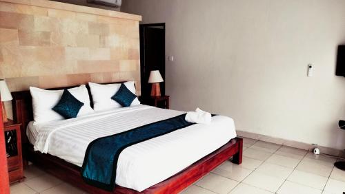 a bedroom with a large white bed with blue pillows at The Green Kamboja Villa in Sanur