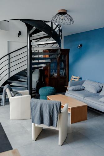 a living room with a table and a spiral staircase at Gîte Ciel - 1-8 pers, au calme, à 20 mins du Puy-de-Dôme, Vulcania et le volcan de Lemptégy in Gelles