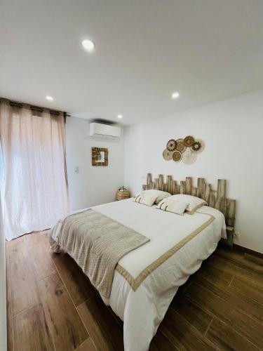 une chambre blanche avec un grand lit et une fenêtre dans l'établissement L effet mer, à Ajaccio