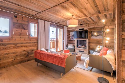 - un salon avec des murs en bois, un canapé et un lit dans l'établissement Duplex des Rois - Welkeys, à Megève