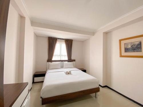 万隆Spacious and Minimalist 3BR at Gateway Pasteur Apartment By Travelio的卧室里有一张白色的床，还有一扇窗户
