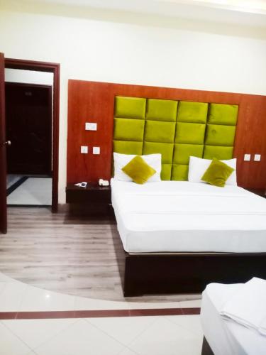 a bedroom with a large white bed with a green headboard at Hotel PAK Continentall Multan in Multan