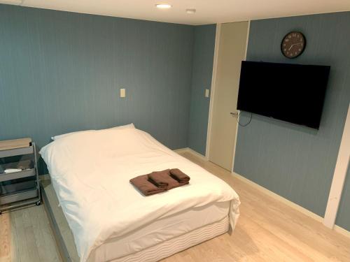 a bedroom with a bed with a tv on the wall at グランディオーソ中野富士見町 in Tokyo