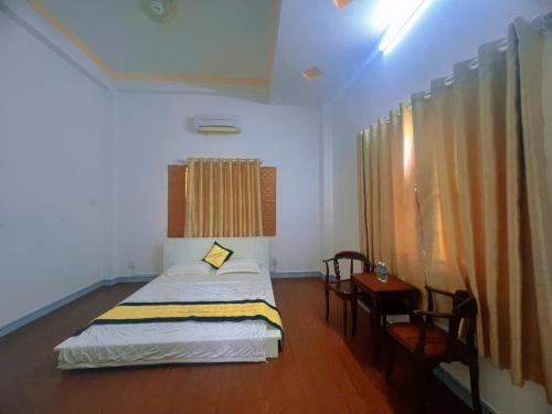 a bedroom with a bed and a table and a window at Can Tho Orchid Garden Homestay in Can Tho