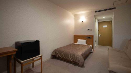 a hotel room with a bed and a tv at Hotel Cocoland in Ube