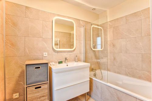 une salle de bain avec un lavabo, une baignoire et un miroir dans l'établissement de Funés, à Trouville-sur-Mer