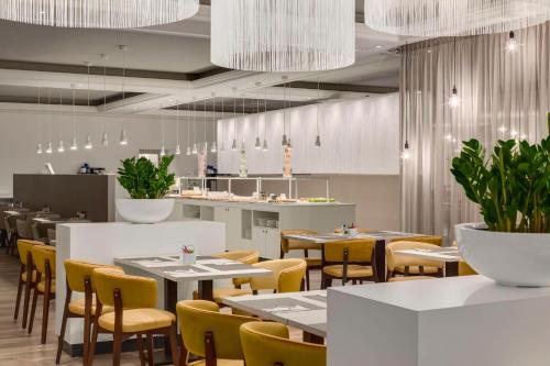 a restaurant with white tables and yellow chairs at NH Collection Gent in Ghent