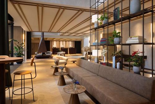a lobby with a couch and some chairs and tables at NH Collection Gent in Ghent