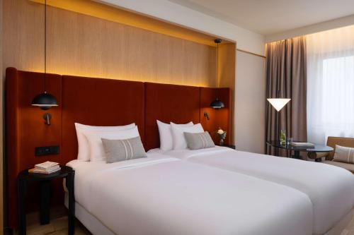 a hotel room with a large bed with white pillows at NH Collection Gent in Ghent
