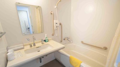 a white bathroom with a sink and a bath tub at Hotel Cocoland in Ube