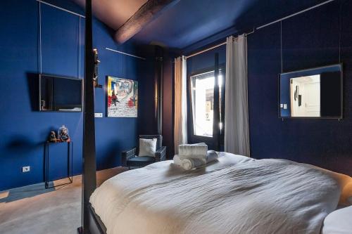 une chambre avec des murs bleus et un grand lit dans l'établissement Maison avec bassin dans les remparts, à Aigues-Mortes