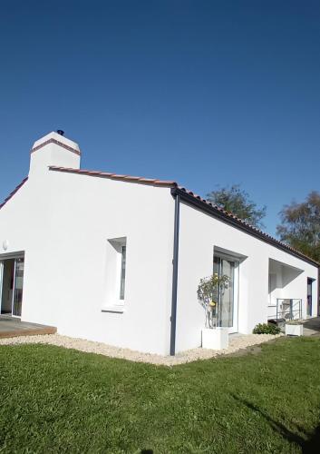 une maison blanche avec une pelouse verte devant elle dans l'établissement Au pied de la forêt, à Saint-Jean-de-Monts
