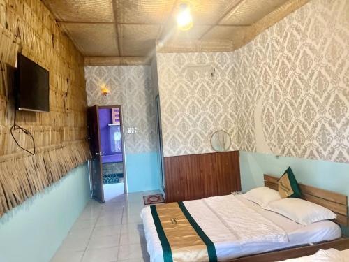 a bedroom with a bed and a tv on a wall at Can Tho Orchid Garden Homestay in Can Tho