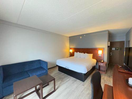 a hotel room with a bed and a blue couch at Super 8 by Wyndham Dallas Love Field Airport in Dallas