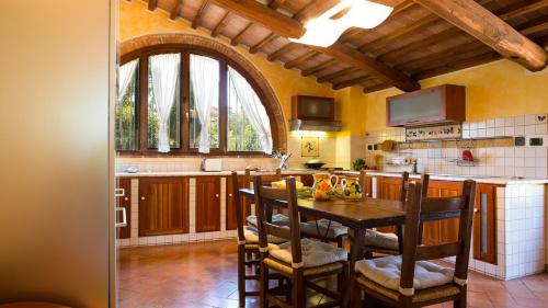 a kitchen with a table and chairs in a kitchen at LA MAGIA 8&2, Emma Villas in Gavorrano
