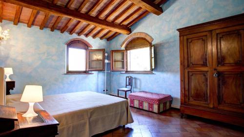 a bedroom with a bed and a chair and windows at LA MAGIA 8&2, Emma Villas in Gavorrano
