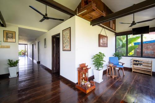 a living room with wooden floors and white walls at Pomelo Outpost Cambodia ដំណាក់ភ្នំក្រោម in Phumĭ Rœssei Lŭk