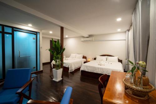 a hotel room with two beds and a table at Pomelo Outpost Cambodia ដំណាក់ភ្នំក្រោម in Phumĭ Rœssei Lŭk
