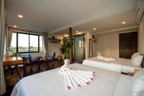 a hotel room with two beds and a table at Pomelo Outpost Cambodia ដំណាក់ភ្នំក្រោម in Phumĭ Rœssei Lŭk