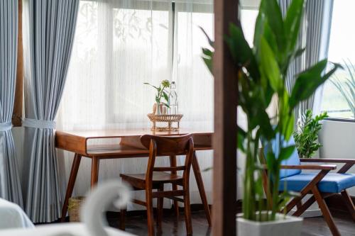 a dining room table with chairs and a window at Pomelo Outpost Cambodia ដំណាក់ភ្នំក្រោម in Phumĭ Rœssei Lŭk