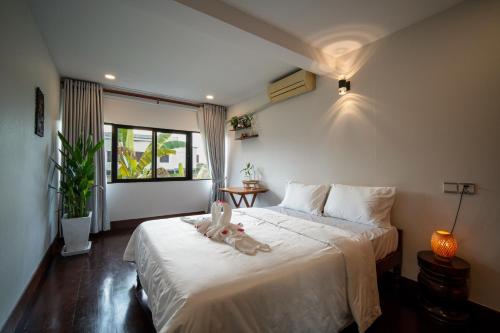 a bedroom with a bed with two stuffed animals on it at Pomelo Outpost Cambodia ដំណាក់ភ្នំក្រោម in Phumĭ Rœssei Lŭk