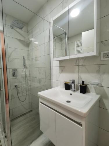 a white bathroom with a sink and a shower at Tri srca in Banja Koviljača