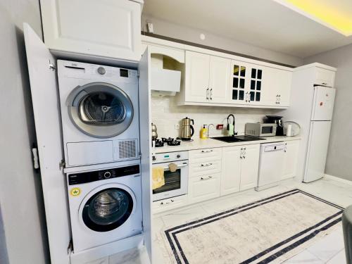 a kitchen with white cabinets and a washer and dryer at Zümrüt villaları in Sapanca