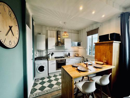 une cuisine avec une table et une horloge au mur dans l'établissement L ESCALE, grand studio près de la gare, à Rennes