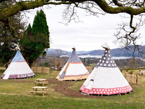 a group of three teepee tents in a field at YHA Windermere in Troutbeck