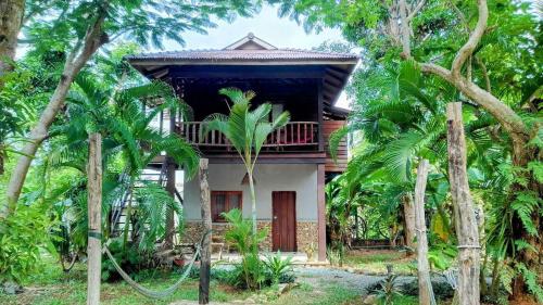 a house with a balcony in the middle of trees at Khmer Hands in Kep