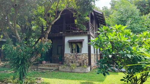 a house with a balcony in the middle of a yard at Khmer Hands in Kep