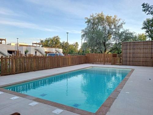 - une piscine dans une cour avec une clôture en bois dans l'établissement Villa T4 jardin clim solarium pisc menage draps, à Vias