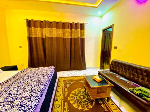 a bedroom with a bed and a couch and a table at Moonlight Guest House in Rawalpindi