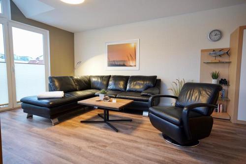 a living room with a leather couch and a coffee table at Ferienwohnungen Auf der Düne in Cuxhaven