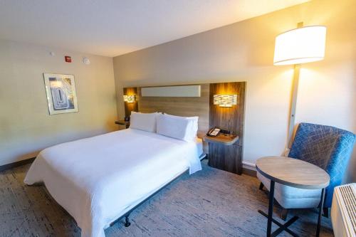 a bedroom with a bed and a table and a chair at Holiday Inn Express - Neptune by IHG in Neptune City