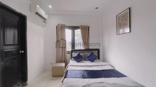 a bedroom with a bed with blue pillows and a window at NamRoom at Kebayoran Baru in Jakarta