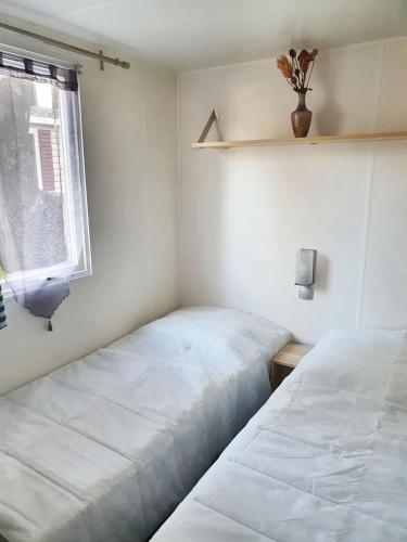 deux lits dans une petite pièce avec une fenêtre dans l'établissement Bungalow charmant à Saint-Jean-de-Monts avec piscine partagée, à Saint-Jean-de-Monts