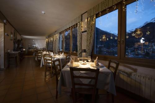 a dining room with tables and chairs and windows at Hotel Des Glaciers in Courmayeur