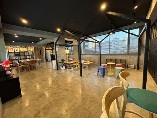 a large room with tables and chairs and windows at Fellows House in Bangkok