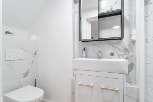 une salle de bain blanche avec un lavabo et un miroir dans l'établissement Arcachon centre 4 couchages accès plage, à Arcachon